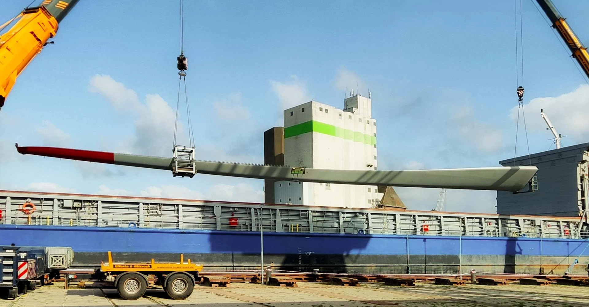 Windkraftanlage wird mit einem Kran von einem Containerschiff gehoben