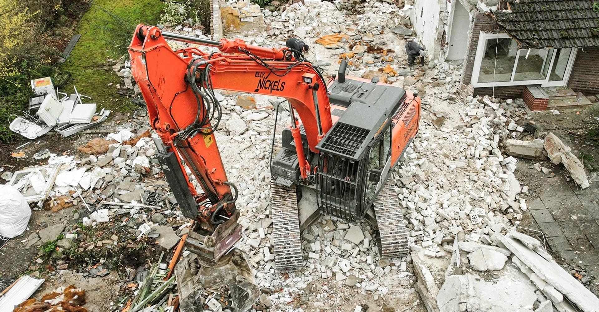 Ein orangeroter Bagger von Elly Nickels auf Schutthaufen von oben fotografiert